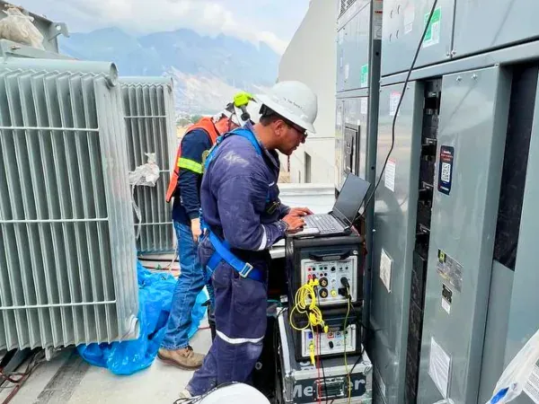 Ingeniero conecta un equipo de pruebas Megger a un tablero de fuerza junto al transformador antes de liberar la alimentación a producción