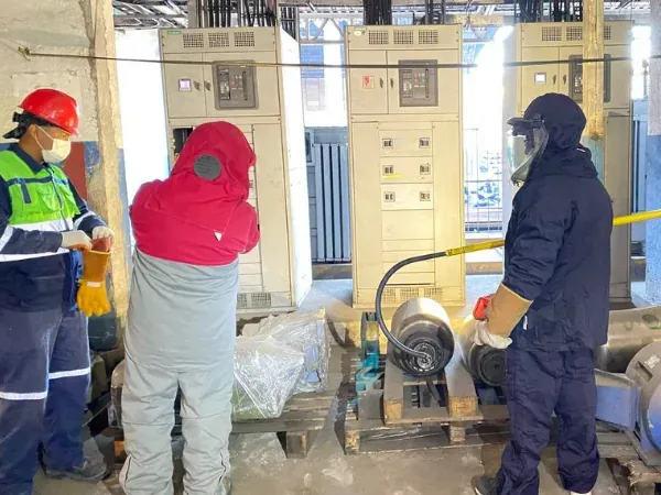 Cuadrilla con traje contra arco eléctrico realizando limpieza dieléctrica de un tablero de distribución en una subestación industrial