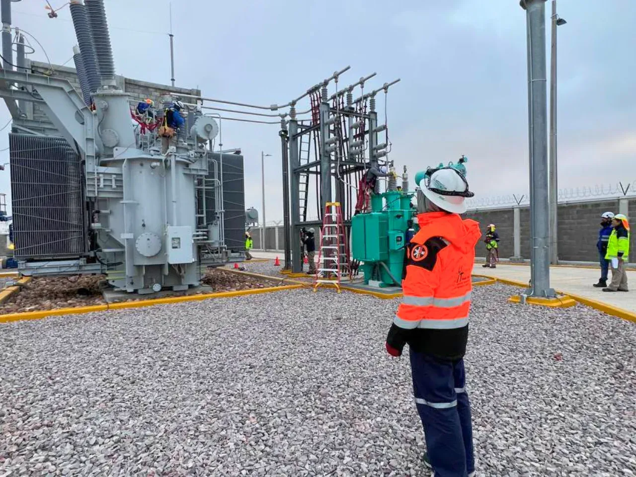 Supervisor de iT Power Systems frente a un transformador de potencia y las cuchillas de una subestación industrial en construcción
