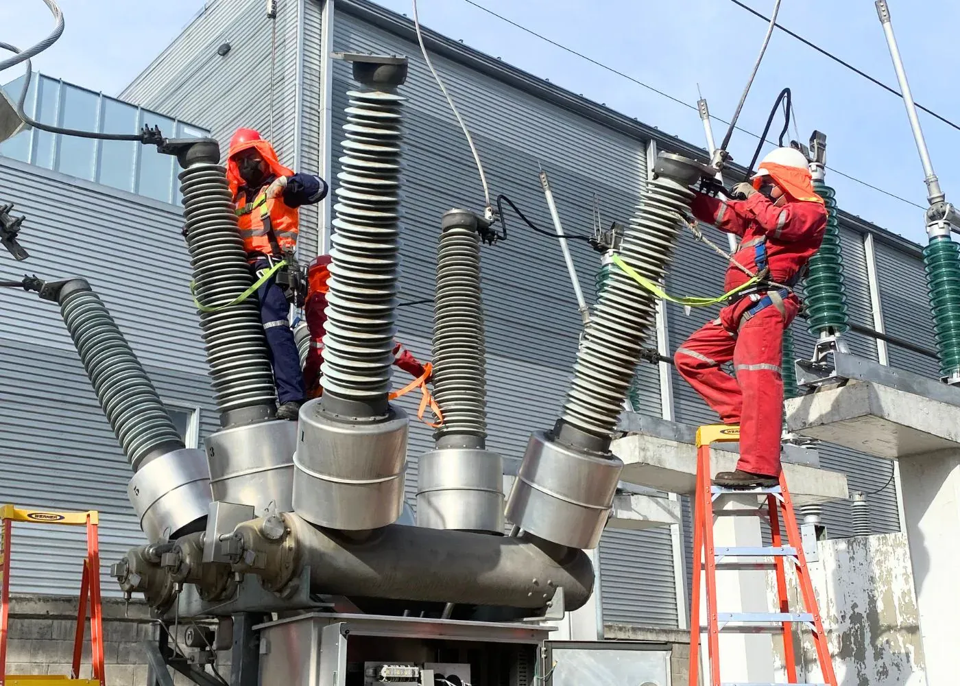 Ingenieros de iT Power Systems maniobrando sobre las boquillas de una subestación eléctrica industrial de alta tensión