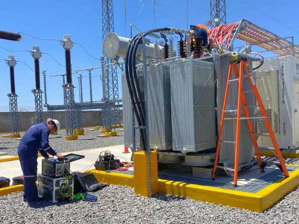 Ingeniero opera un equipo de pruebas frente al transformador de potencia que alimenta la nave, en el patio de la subestación